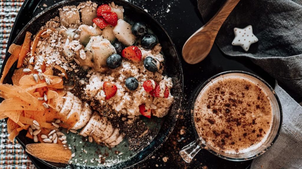 Delicious oatmeal breakfast bowl with fresh fruits and a cup of coffee.