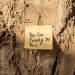 A sticky note with a motivational message on a textured wall in Dubai, with sunlight casting shadows.