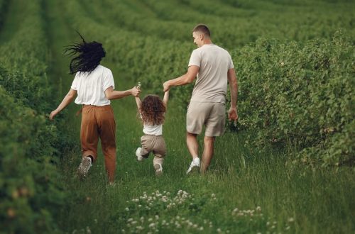 A joyful family strolls through a lush green field, enjoying quality time together.